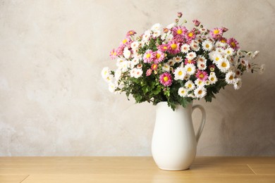 Photo of Vase with beautiful flowers on pink wooden table, space for text