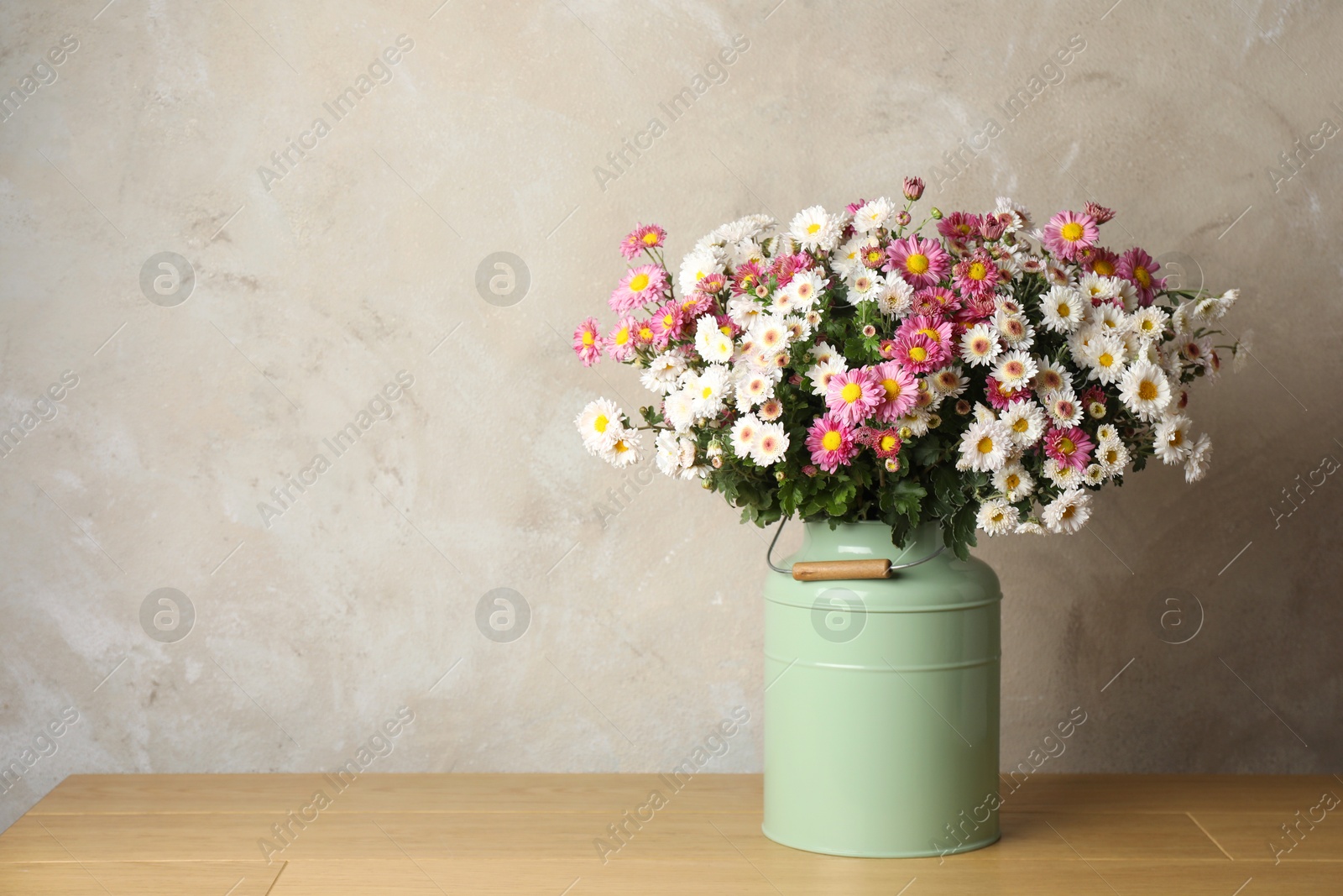 Photo of Beautiful flowers in modern vase on wooden table, space for text