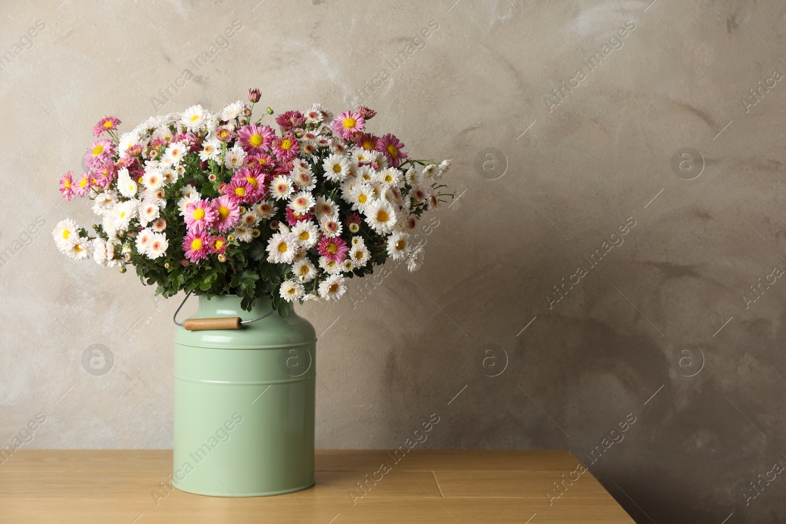 Photo of Beautiful flowers in modern vase on wooden table. Space for text