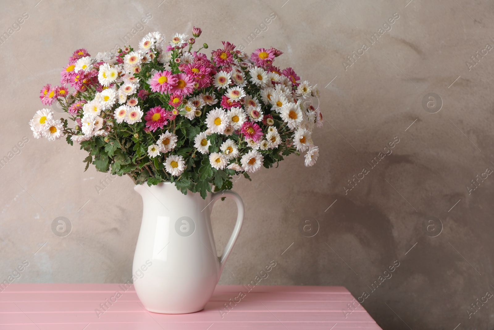 Photo of Vase with beautiful flowers on pink wooden table