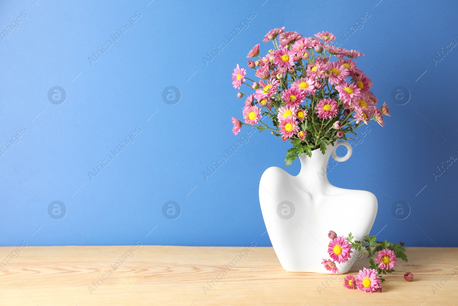 Photo of Stylish vase with beautiful flowers on wooden table. Space for text