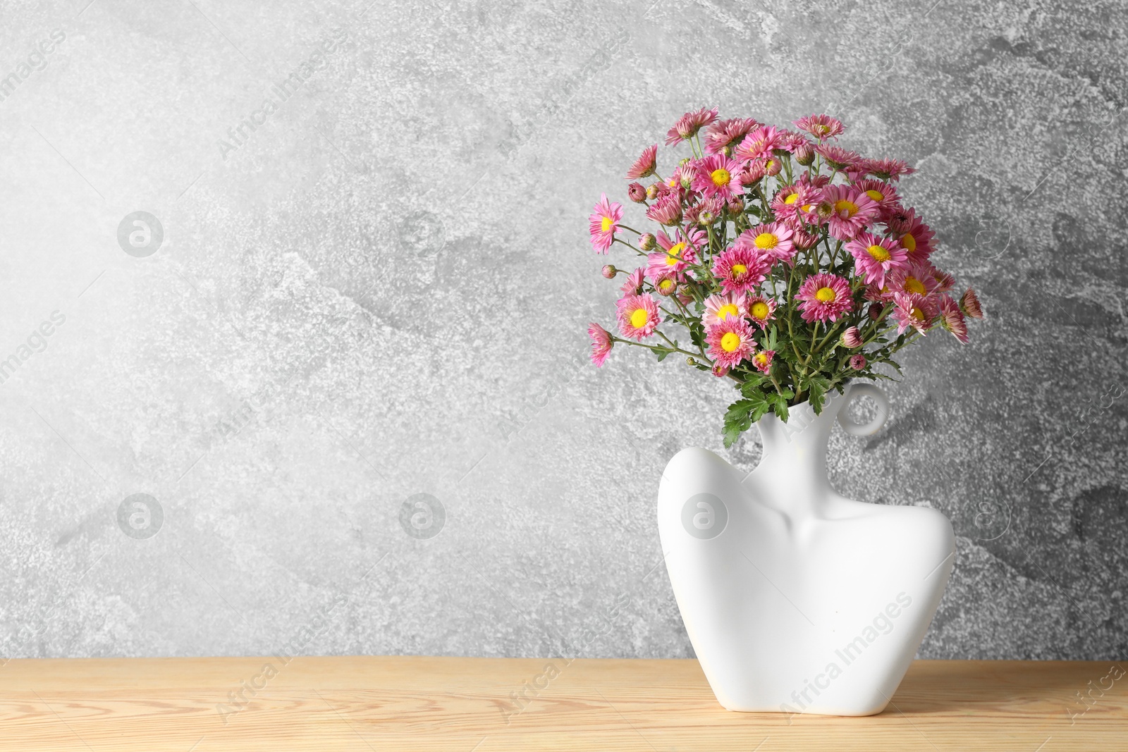 Photo of Stylish vase with beautiful flowers on wooden table. Space for text