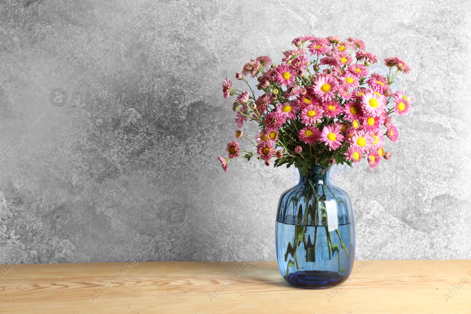 Photo of Vase with beautiful flowers on wooden table. Space for text