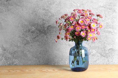 Photo of Vase with beautiful flowers on wooden table. Space for text