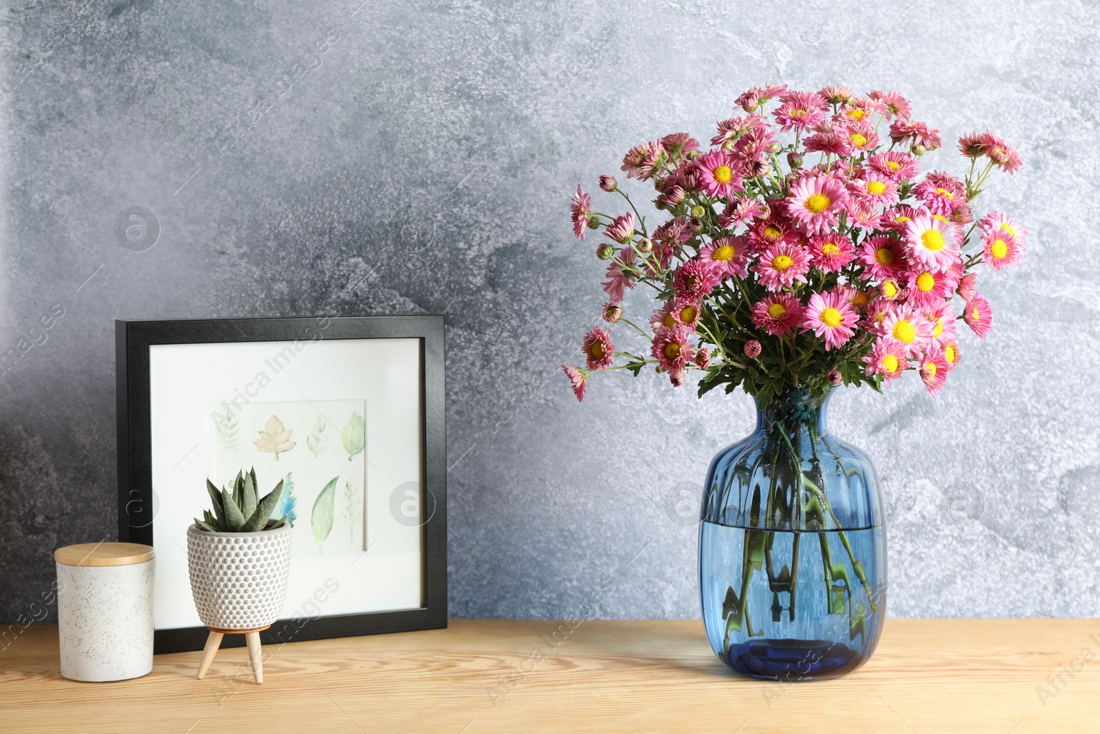 Photo of Beautiful flowers in vase and decor on wooden table