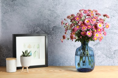 Photo of Beautiful flowers in vase and decor on wooden table