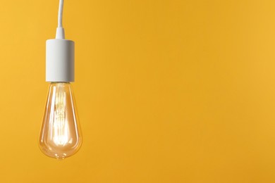 Photo of Light bulb against orange background, space for text