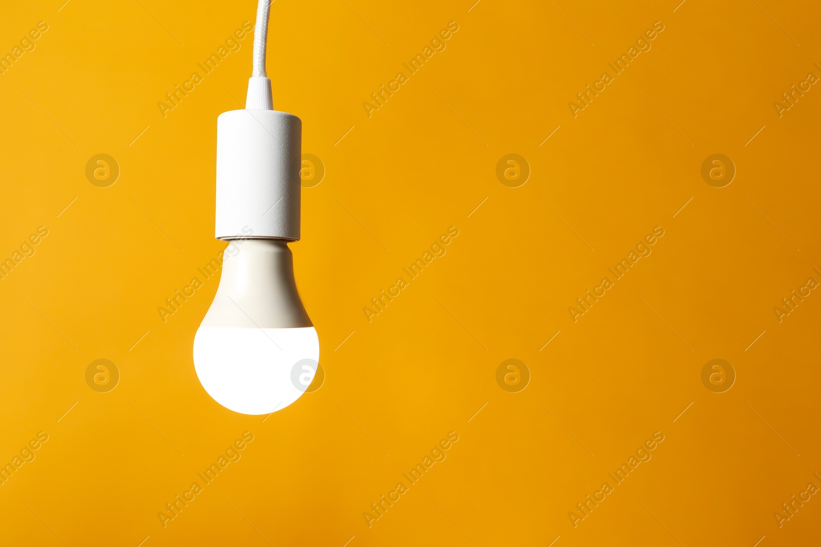 Photo of Light bulb against orange background, space for text