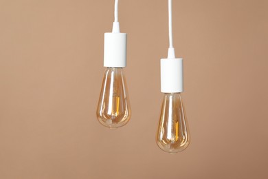 Photo of Light bulbs hanging on cords against beige background