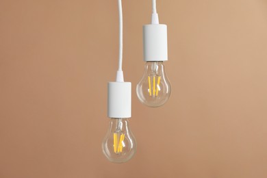 Photo of Light bulbs hanging on cords against beige background