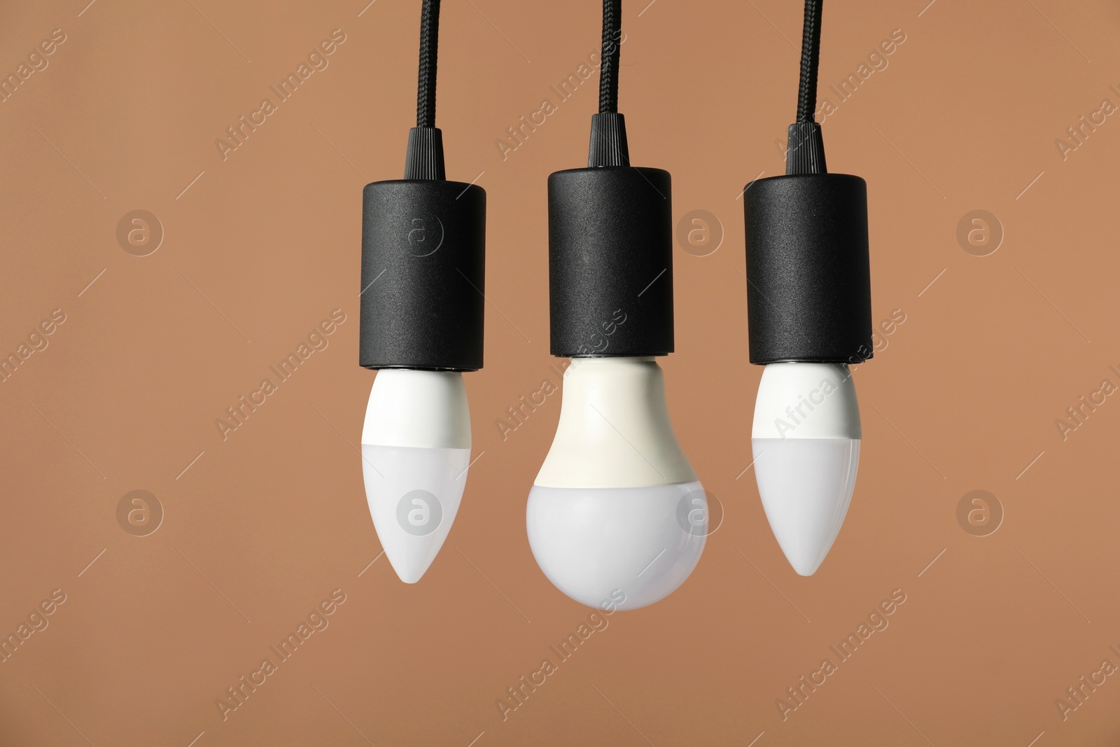 Photo of Light bulbs hanging on cords against beige background