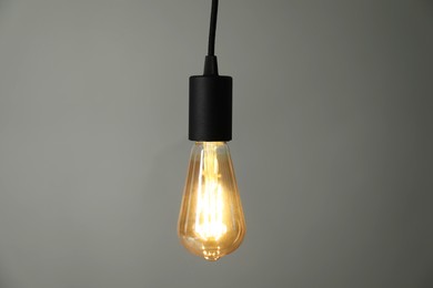 Photo of Light bulb hanging on cord against grey background