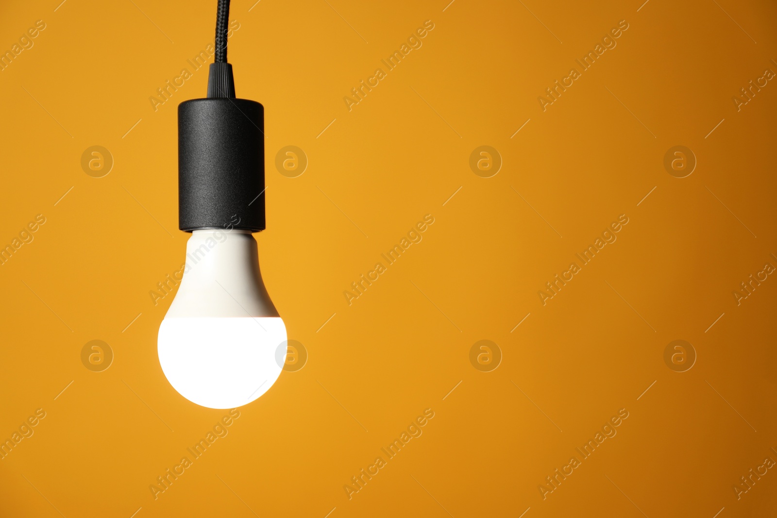 Photo of Light bulb against orange background, space for text