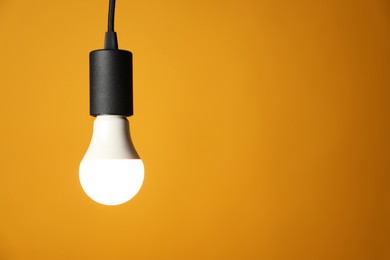 Photo of Light bulb against orange background, space for text