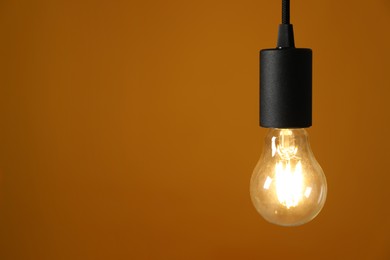 Photo of Light bulb against orange background, space for text