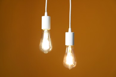 Photo of Light bulbs hanging on cords against orange background