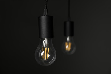 Photo of Light bulbs hanging on cords against grey background, selective focus. Space for text