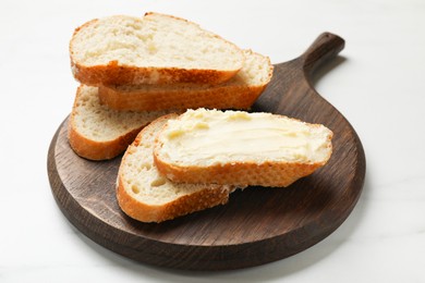Photo of Fresh bread with butter on white table, closeup