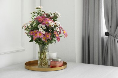 Photo of Beautiful flowers in vase and candles on white wooden table at home