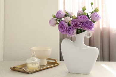 Photo of Stylish vase with beautiful flowers and decor on white wooden table at home