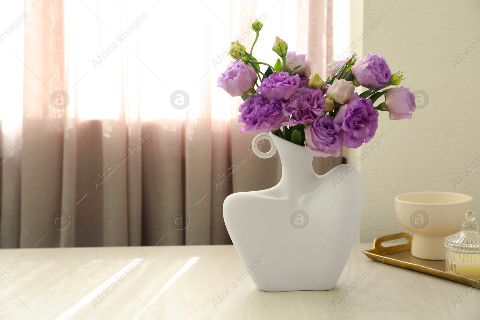 Photo of Stylish vase with beautiful flowers and decor on white wooden table at home, space for text