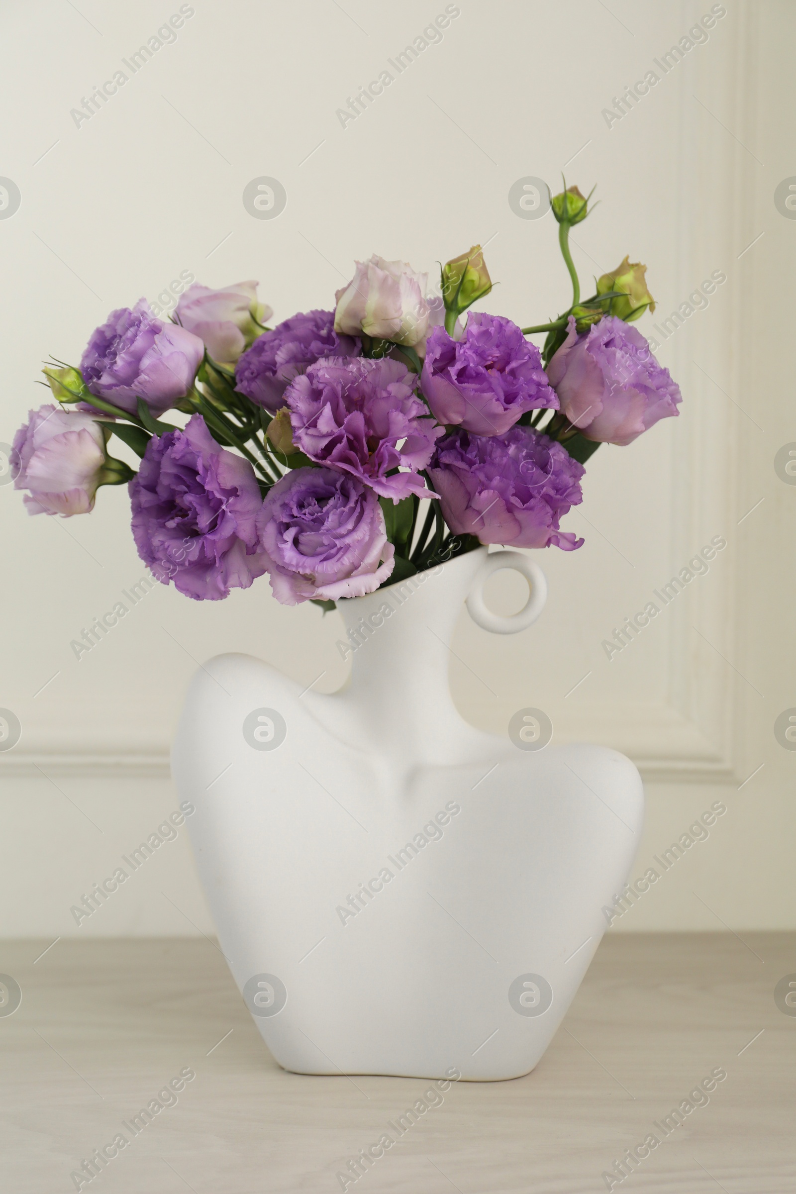 Photo of Stylish vase with beautiful flowers on white wooden table at home