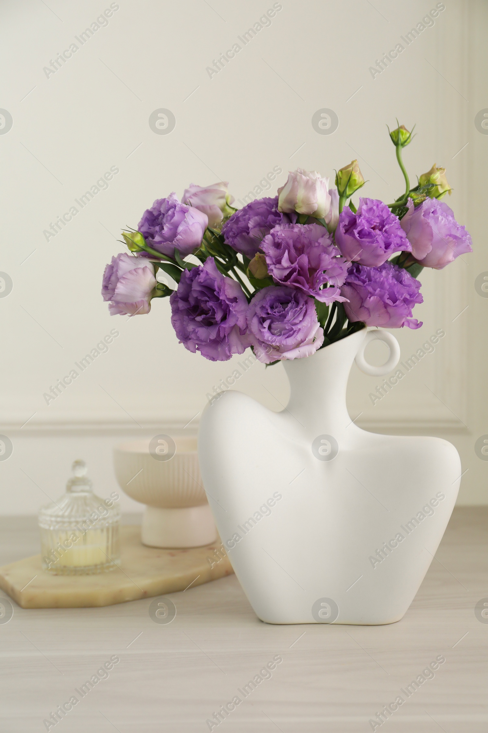 Photo of Stylish vase with beautiful flowers and decor on white wooden table at home