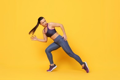 Beautiful woman in sportswear training on yellow background