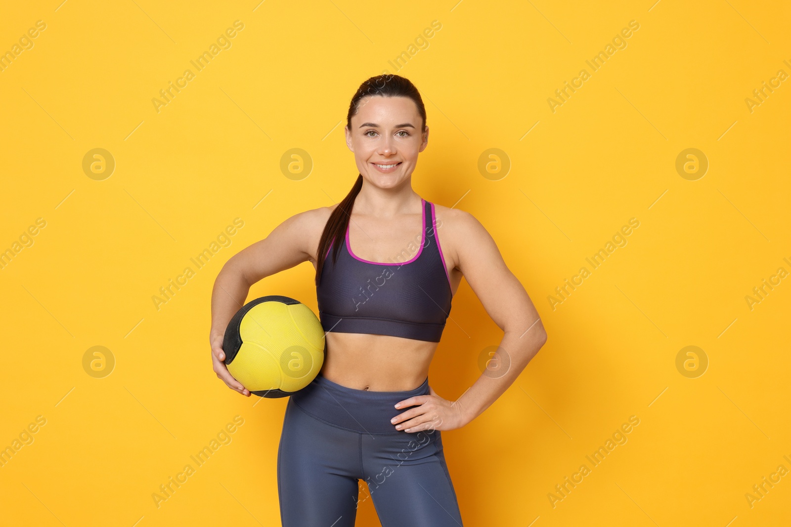 Photo of Smiling woman with fitness ball on yellow background