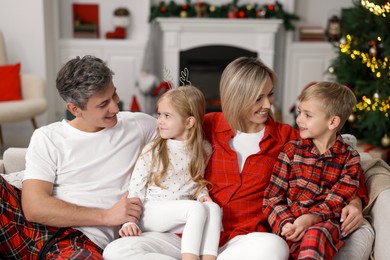 Photo of Happy family in pajamas on sofa at home. Christmas morning