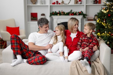 Photo of Happy family in pajamas on sofa at home. Christmas morning