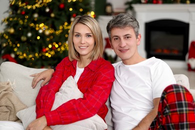 Photo of Lovely couple in pajamas on sofa at home. Christmas morning