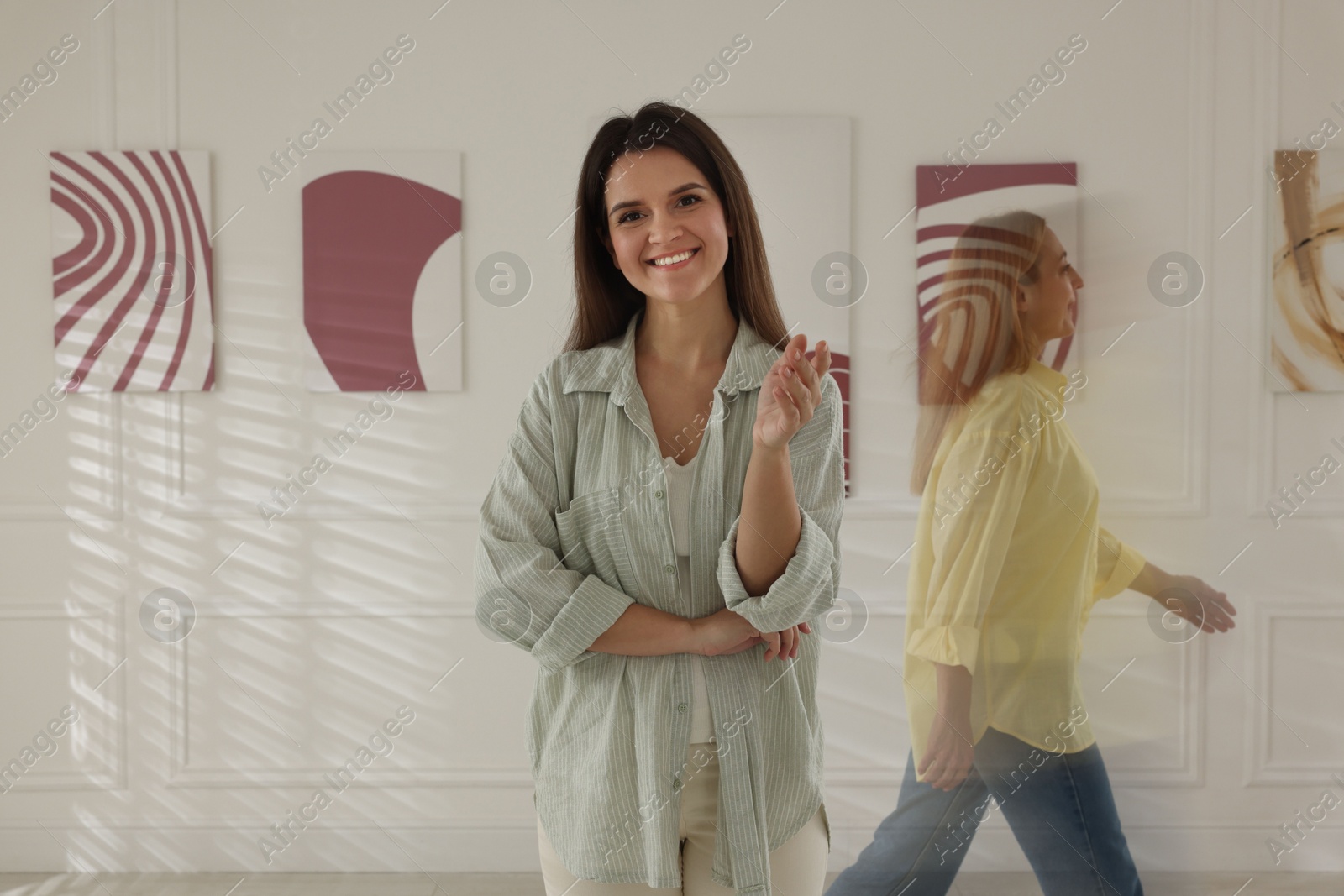 Photo of Woman in art gallery and people passing by, motion blur effect