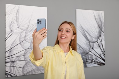 Photo of Woman taking selfie with paintings in art gallery