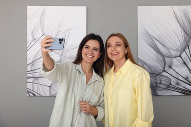 Friends taking selfie with paintings in art gallery