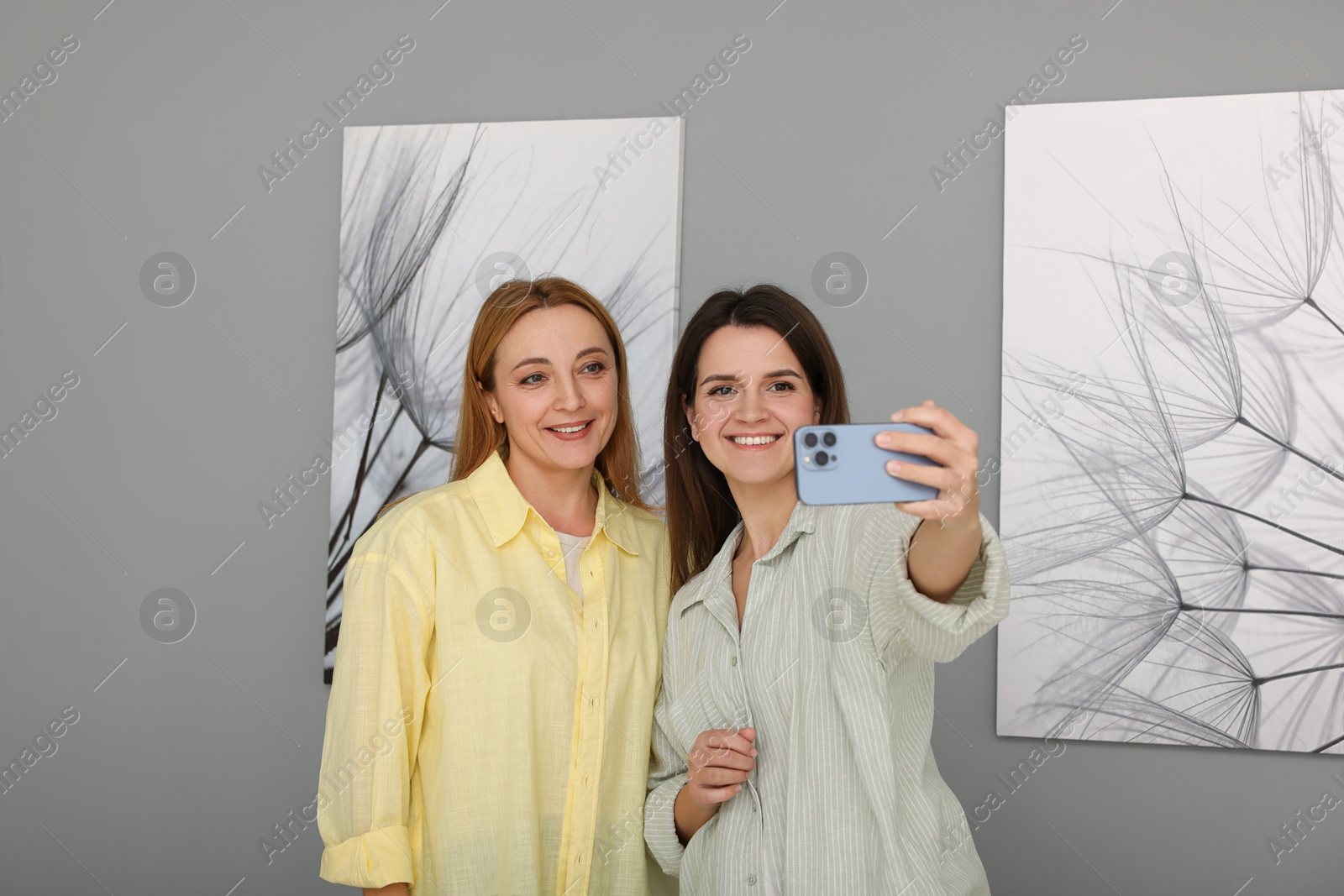 Photo of Friends taking selfie with paintings in art gallery