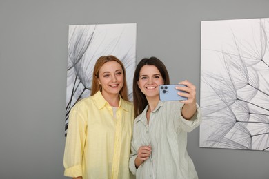 Friends taking selfie with paintings in art gallery