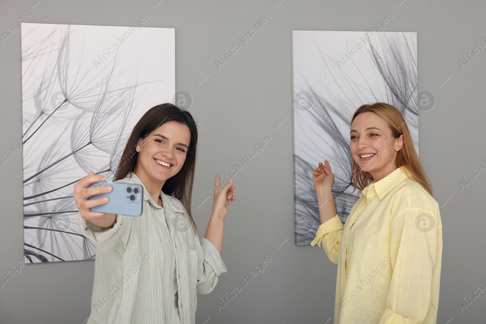 Photo of Friends taking selfie with paintings in art gallery