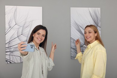 Friends taking selfie with paintings in art gallery