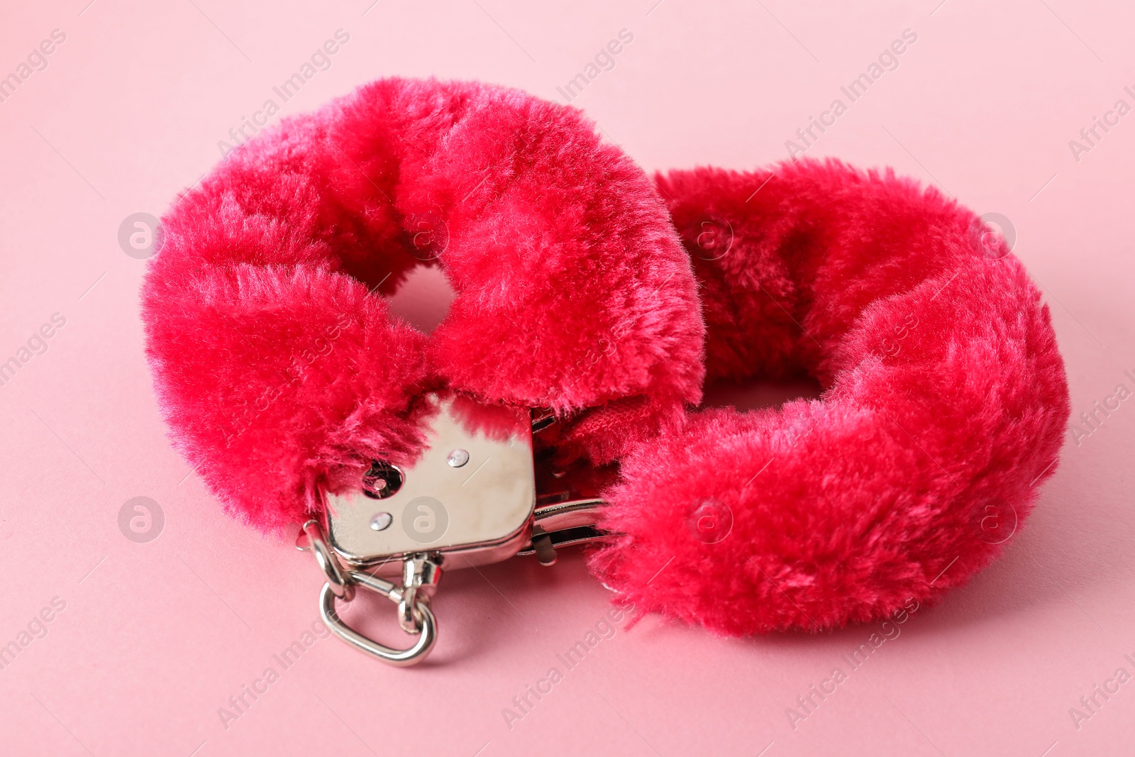 Photo of Fluffy handcuffs on pink background, closeup. Sex toy