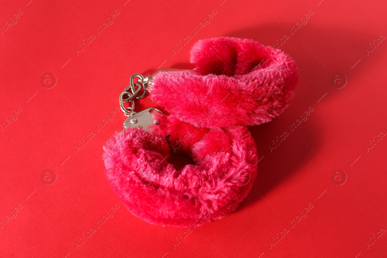 Photo of Pink fluffy handcuffs on color background. Sex toy