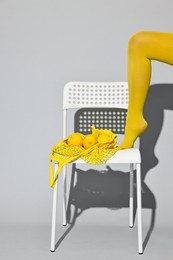 Photo of Woman with net bag and lemons on chair against light grey background, closeup