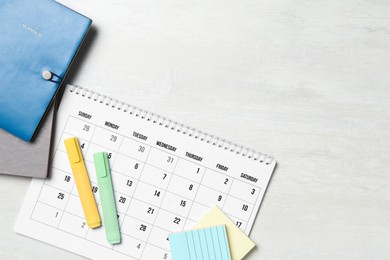 Timetable. Monthly planner and stationery on white wooden table, flat lay. Space for text