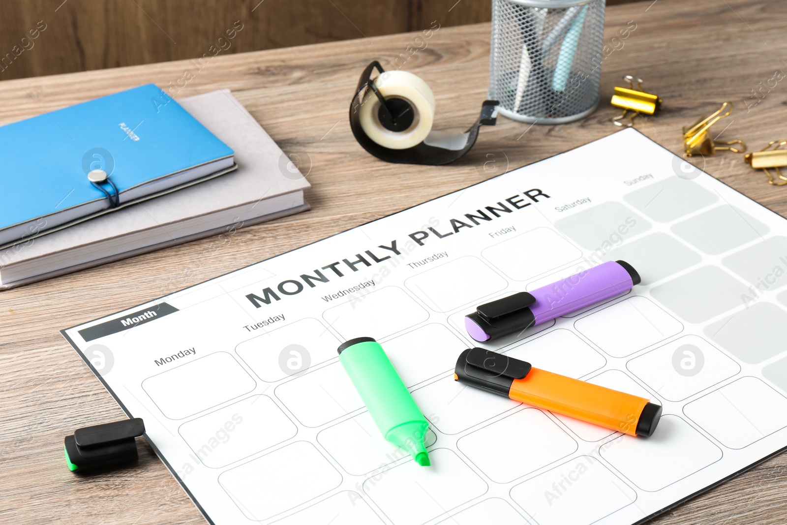 Photo of Timetable. Monthly planner and stationery on wooden table, closeup