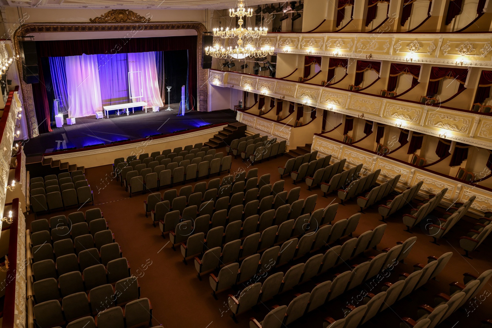 Photo of Theatre interior with stage, rows of comfortable seats and beautiful chandelier