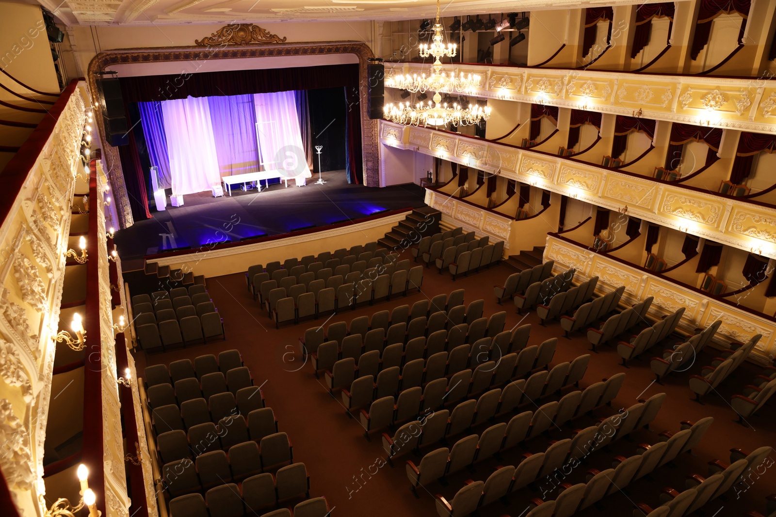 Photo of Theatre interior with stage, rows of comfortable seats and beautiful chandelier