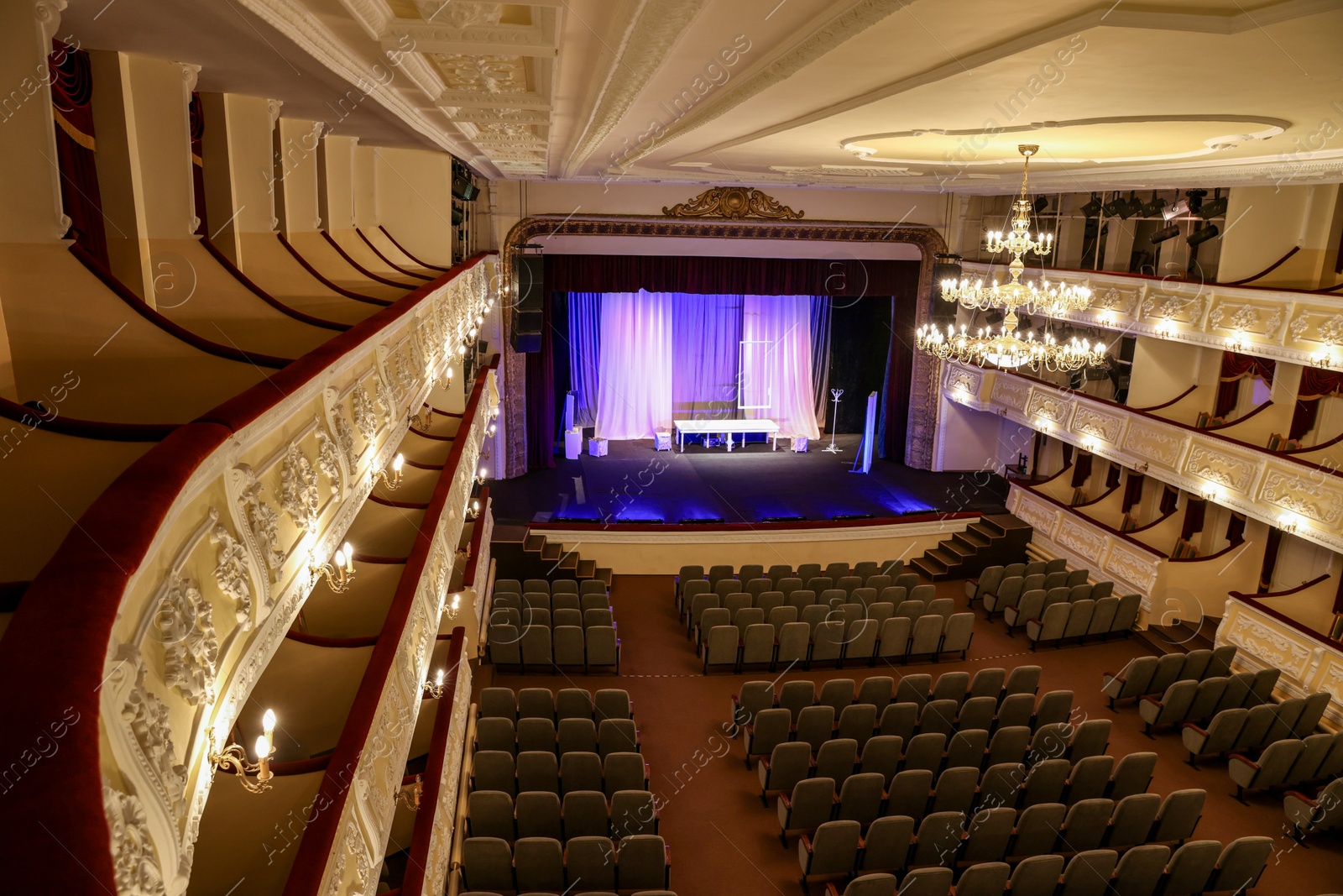 Photo of Theatre interior with stage, rows of comfortable seats and beautiful chandelier