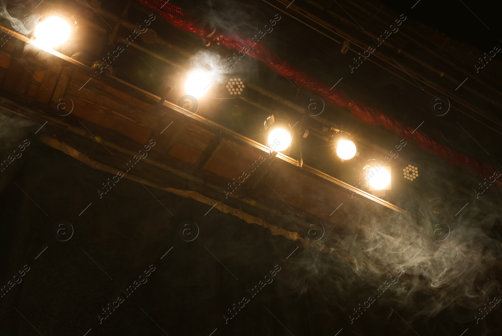 Photo of Professional spotlights and smoke on stage in theatre, low angle view