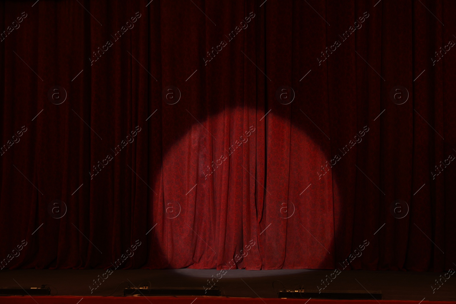 Photo of Elegant closed red curtains illuminated by spotlight in theatre