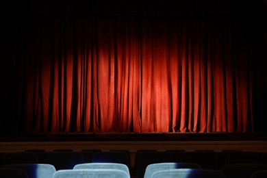 Photo of Elegant closed red curtains illuminated by spotlight in theatre